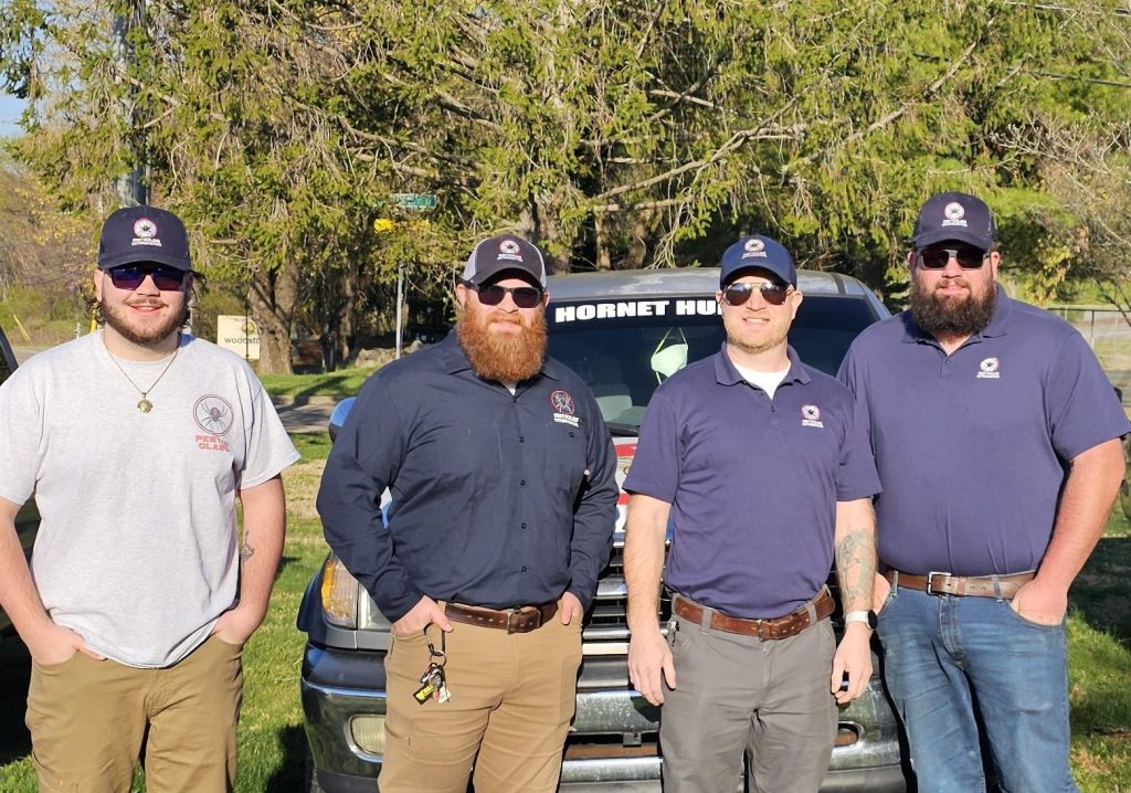 The owners and employees of Pest In Class Exterminating stand before their trucks with the tools of their trade.